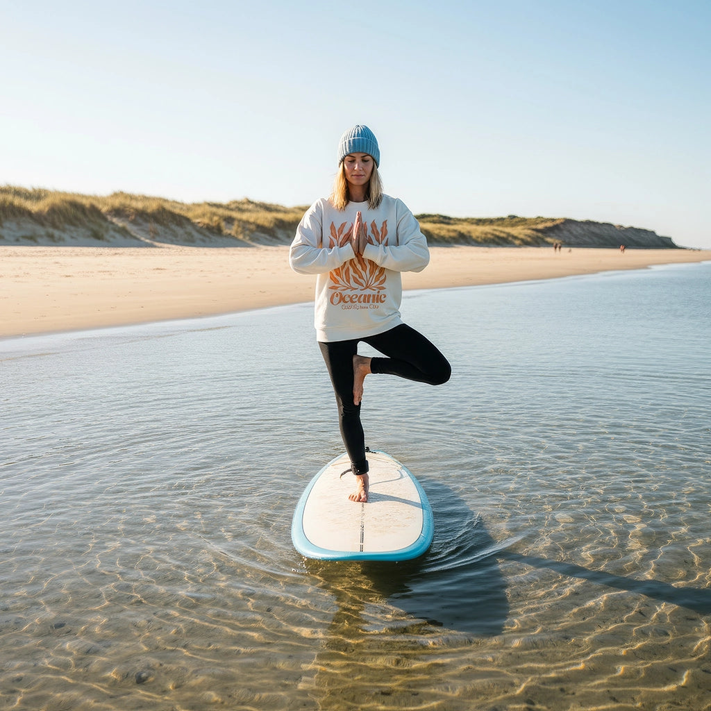 <img src="Oceanic-Club-Sweatshirt-offwhite-front-woman-sup-yoga-tree-pose_1024px.webp" alt="Frau in Oceanic Club Sweatshirt in Off-White mit großem Algen-Print in ausgeblichenem Orange auf der Front: Praktiziert SUP-Yoga in der Baumpose auf einem Stand-Up-Paddleboard, umgeben von ruhigem Wasser, gefertigt aus 100% GOTS-zertifizierter Bio-Baumwolle">