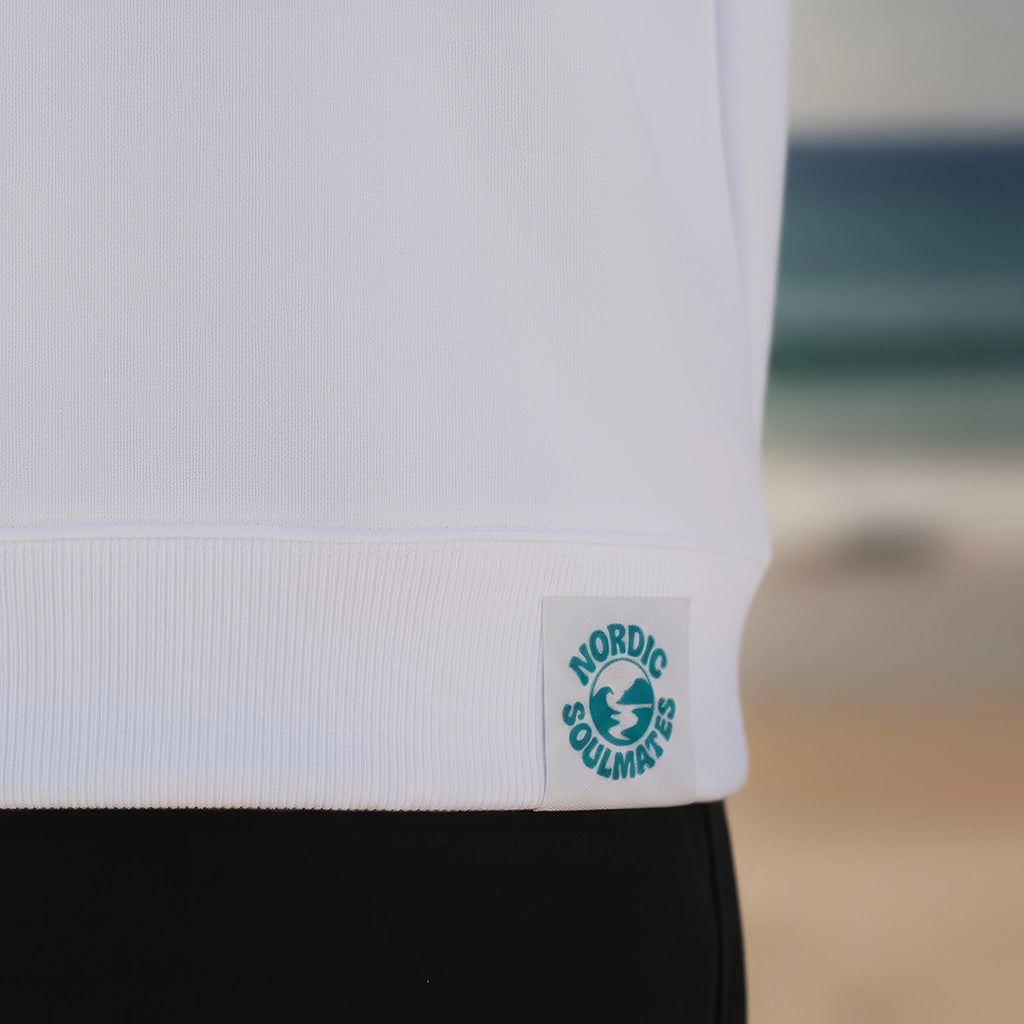 <img src="tide-chaser-hoodie-off-white-webetikett-detail.jpg" alt="Detailaufnahme des Webetiketts am Saum des Tide-Chaser Hoodie in Off-White: GOTS-zertifizierte Bio-Baumwolle, Markenlogo und Pflegehinweise in Nahansicht, gefertigt aus 100% gekämmter, ringgesponnener Bio-Baumwolle">