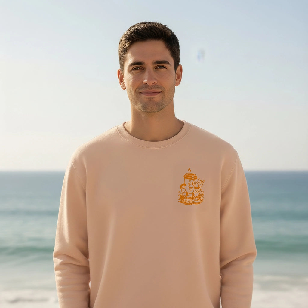 <img src="Hot-Coffee-Cold-Waves-Sweatshirt-fraiche-peche-front-Man-closeup_1024px.webp" alt="Mann am Strand in Frontansicht, trägt das Hot Coffee Cold Waves Sweatshirt in Fraîche Pêche: Blick in die Kamera, kleiner Brustprint mit maritimen Motiven, natürliche Küstenatmosphäre, gefertigt aus 100% GOTS-zertifizierter Bio-Baumwolle">