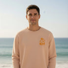 <img src="Hot-Coffee-Cold-Waves-Sweatshirt-fraiche-peche-front-Man-closeup_1024px.webp" alt="Mann am Strand in Frontansicht, trägt das Hot Coffee Cold Waves Sweatshirt in Fraîche Pêche: Blick in die Kamera, kleiner Brustprint mit maritimen Motiven, natürliche Küstenatmosphäre, gefertigt aus 100% GOTS-zertifizierter Bio-Baumwolle">