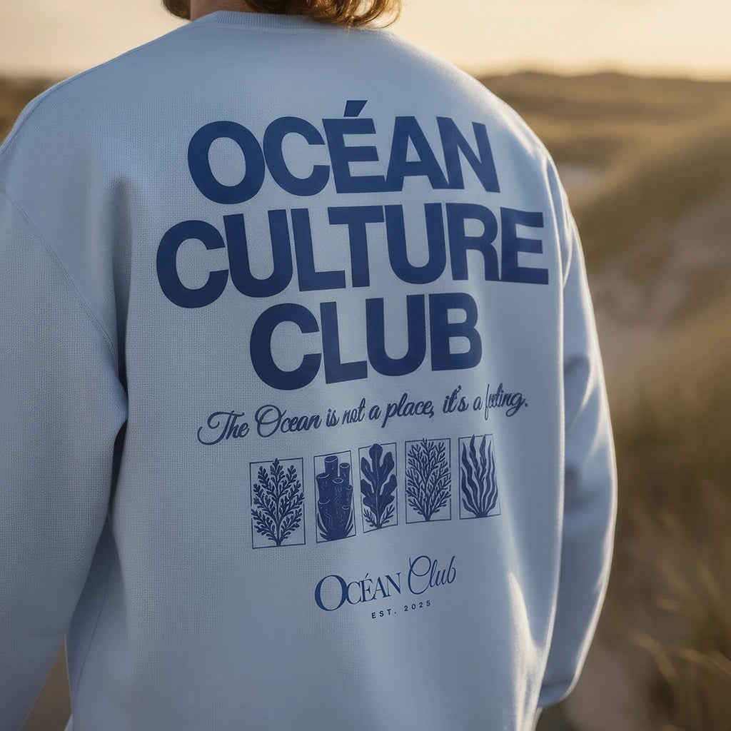 <img src="Ocean-Culture-Club-Sweatshirt-blue-soul-back-man-walking-Longboard-1024px.webp" alt="Mann mit Longboard, trägt das Ocean Culture Club Sweatshirt in Blue Soul (hellblau): Close-Up des großen Backprints mit Schriftzug 'Ocean Culture Club' und gradlinigen Illustrationen von Wasserpflanzen, Algen und Korallen, unscharfe Dünen im Hintergrund, entspannte Küstenatmosphäre, gefertigt aus 100% GOTS-zertifizierter Bio-Baumwolle">