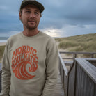 <img src="Tide-and-Time-Sweatshirt-stone-front-man-Beachclub-standing_1024px.webp" alt="Lächelnder Mann steht auf einem Steg zum Strandcafé, trägt das Tide and Time Sweatshirt in Stone: kreisförmiger Frontprint mit stilisierter Welle und Schriftzug 'Nordic Soulmates', Blick in die Ferne, maritime Atmosphäre mit Dünen im Hintergrund, gefertigt aus 100% GOTS-zertifizierter Bio-Baumwolle">